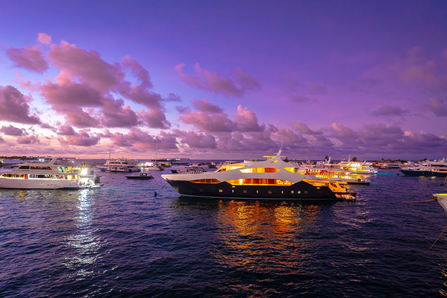Small liveaboard dive boat anchored in calm open water at sunset