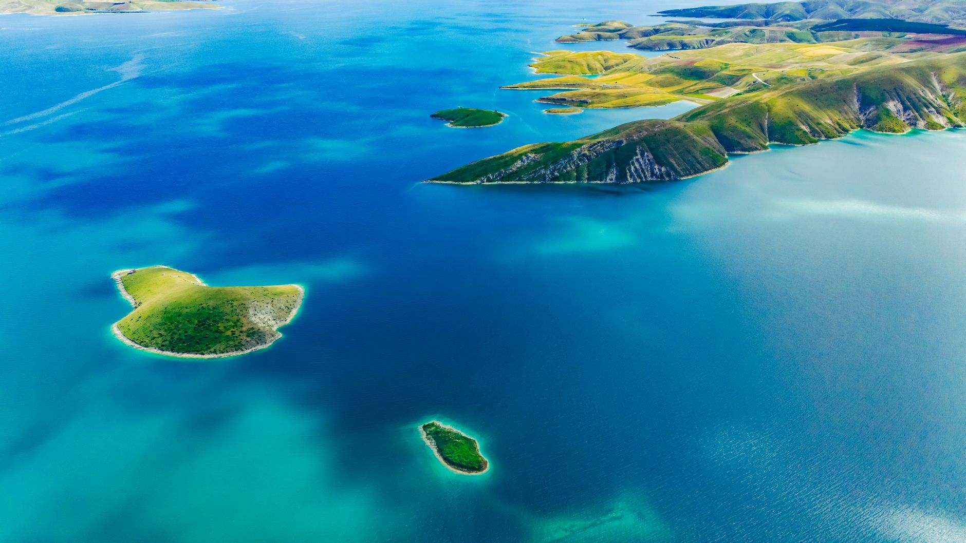 Aerial view of a remote uninhabited island surrounded by turquoise shallow water