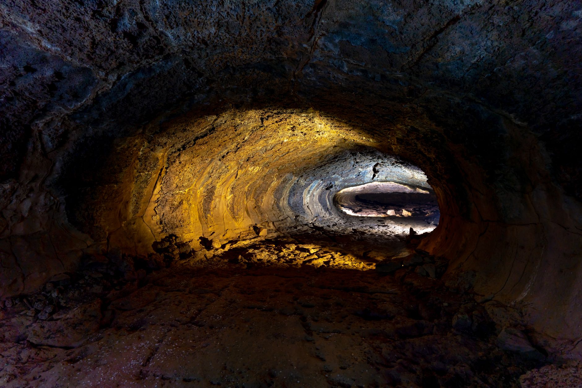 Interior of a large lava tube cave with rocky walls and dark chambers