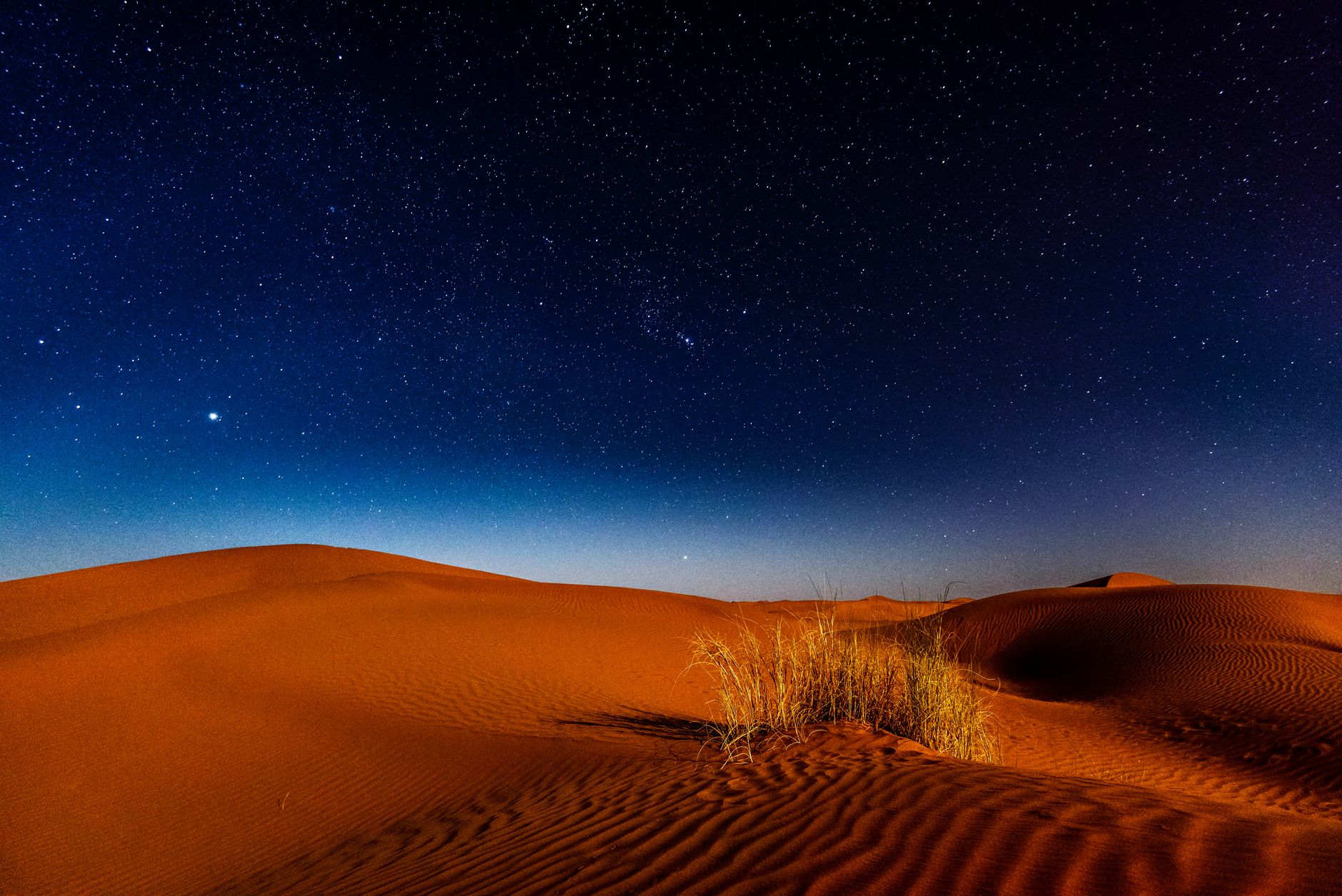 Milky Way visible above a flat desert landscape with distant sandstone formations