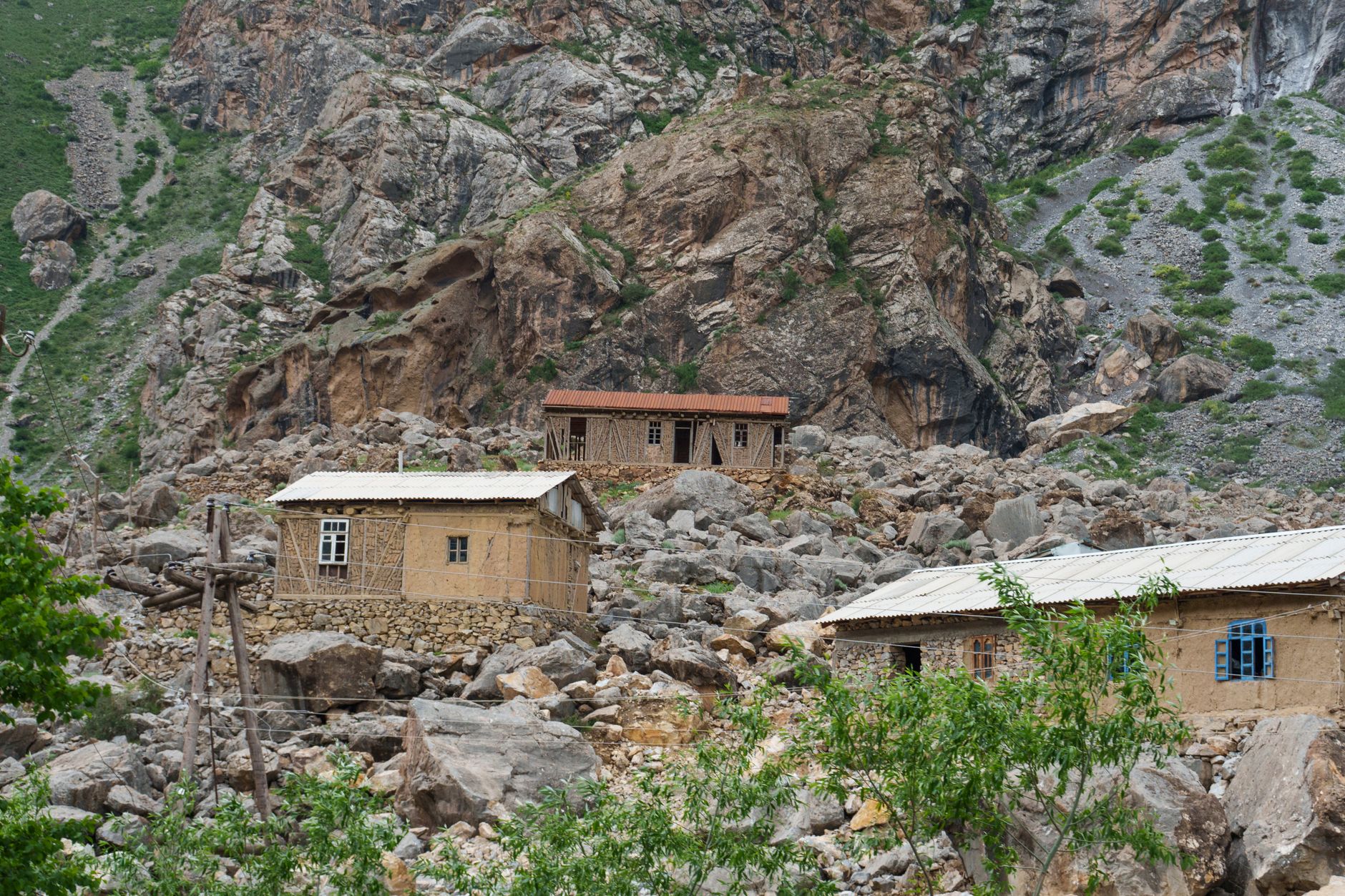 Small stone and timber village nestled in a deep mountain valley under cloudy skies