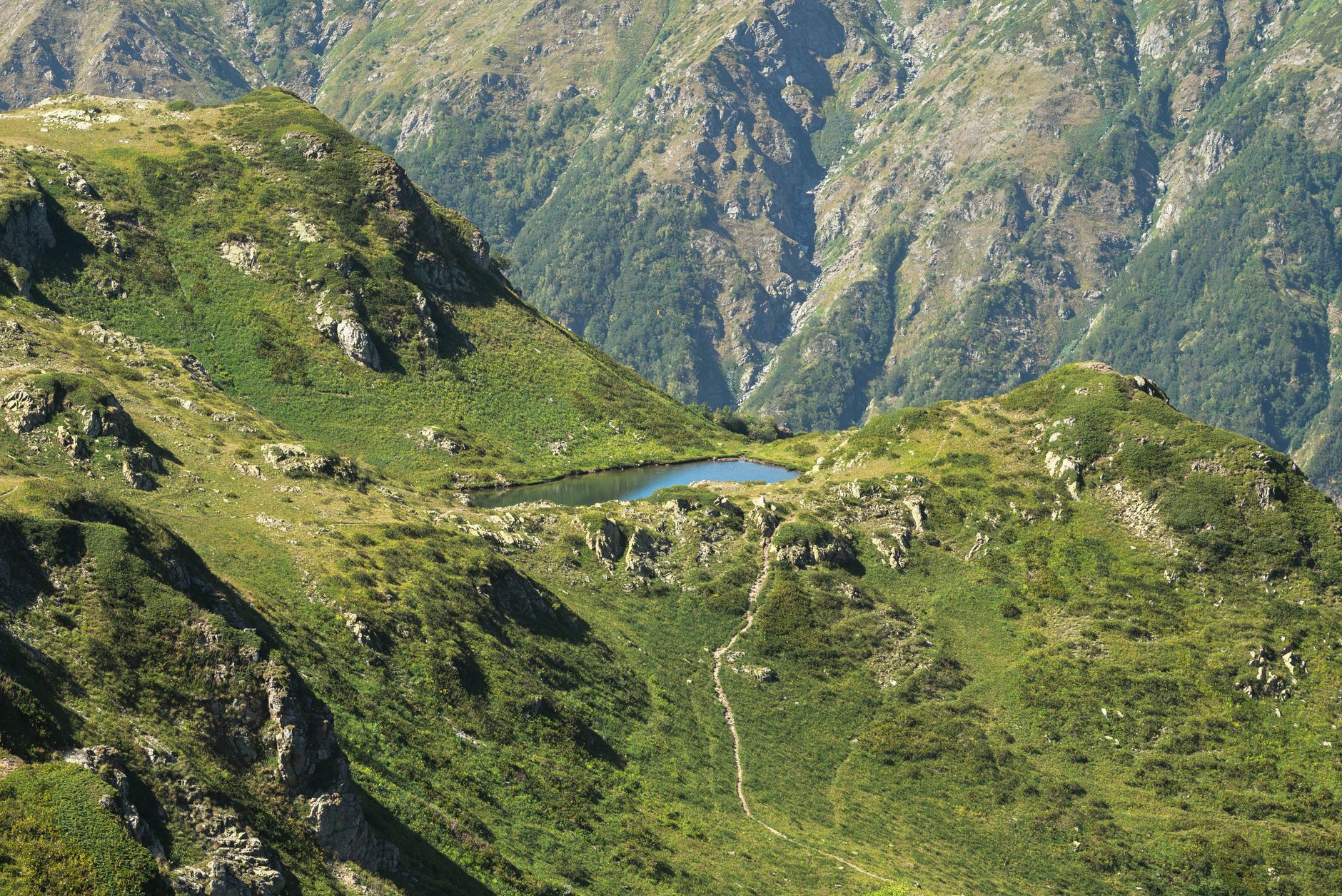 Hiker on a high alpine trail with dramatic mountain ridgeline views in the Caucasus