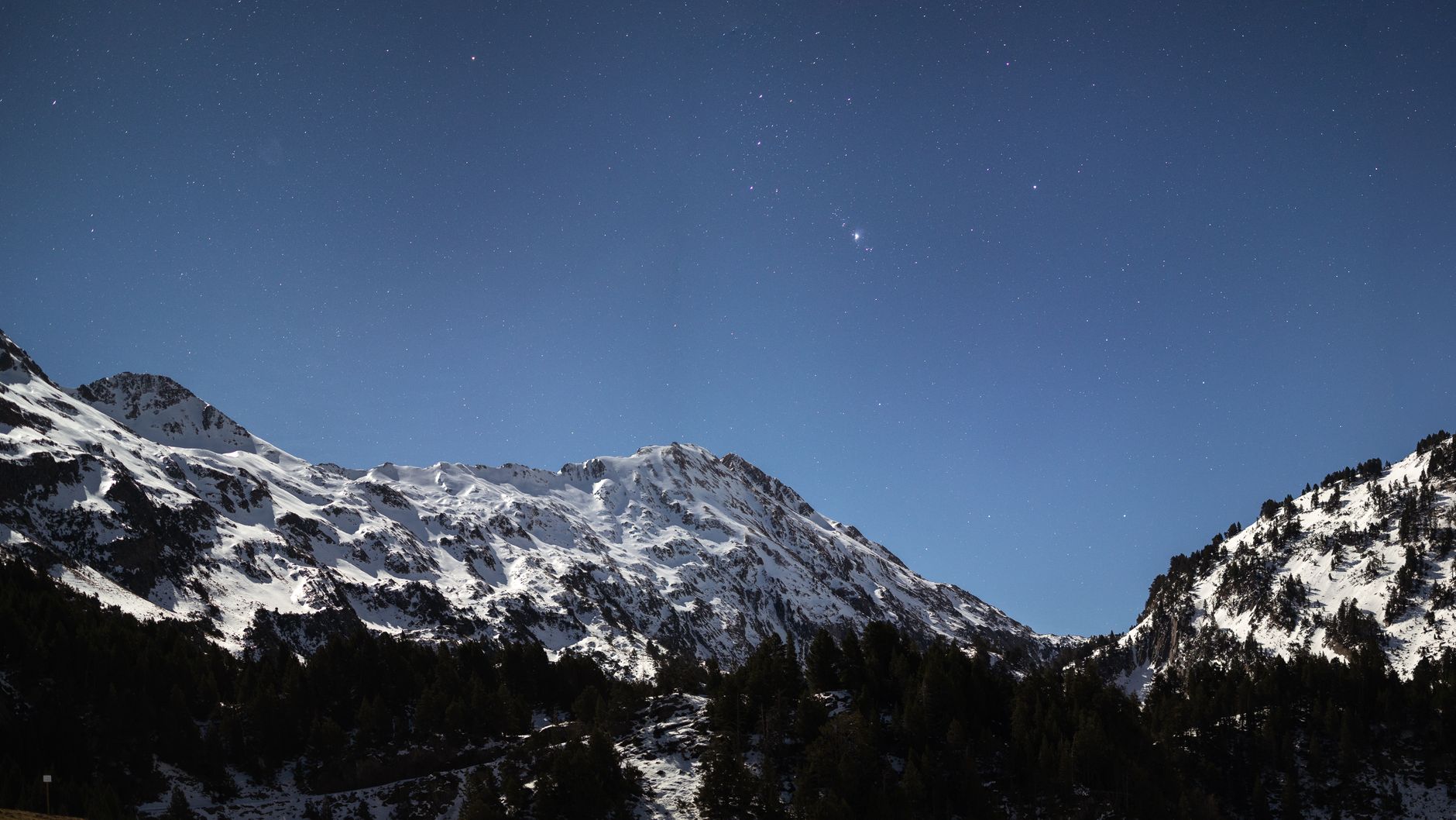 A clear starlit night sky over a remote mountain landscape with no artificial light pollution