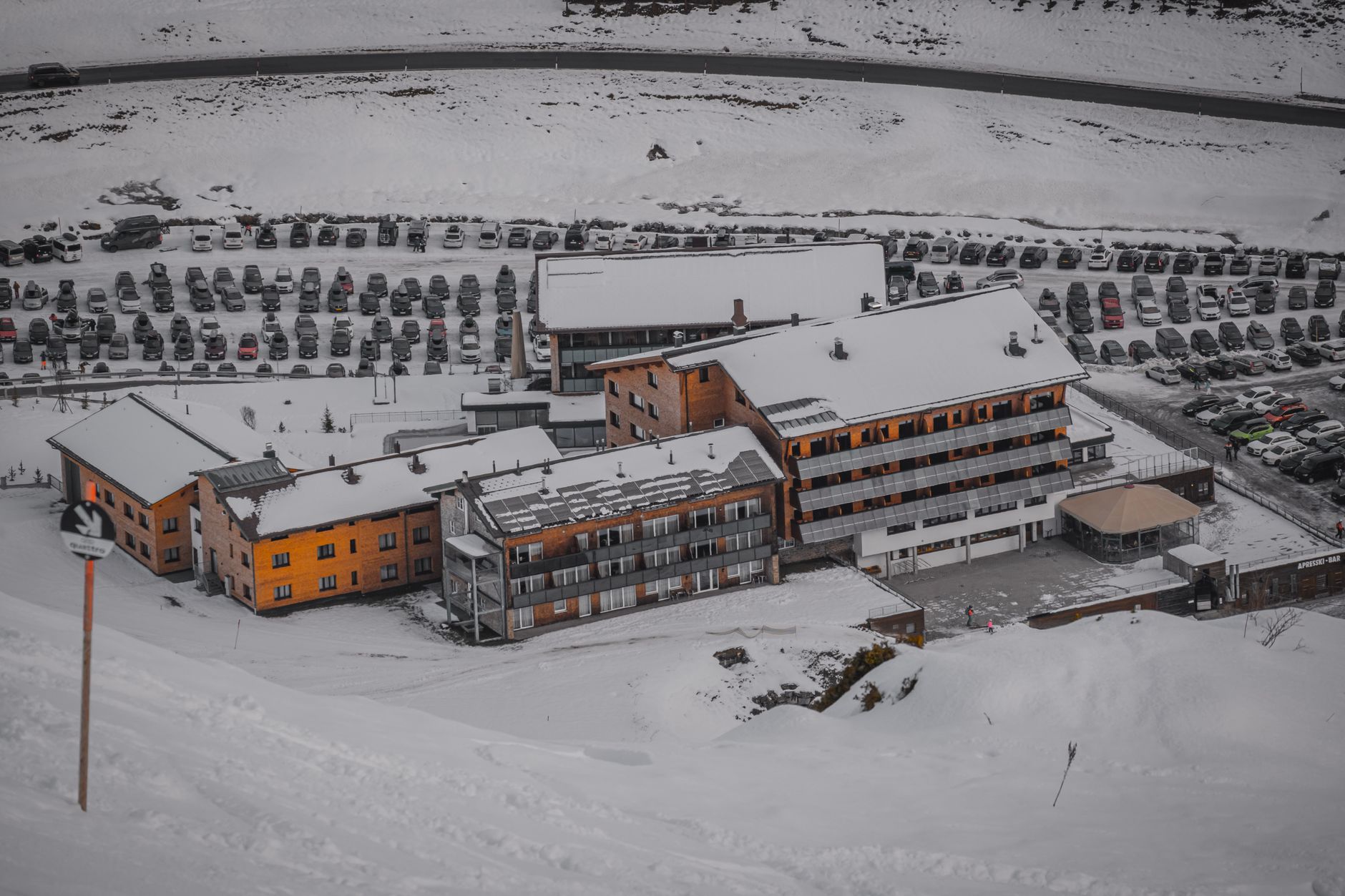A stone mountain lodge dusted with snow against a clear winter sky at high altitude